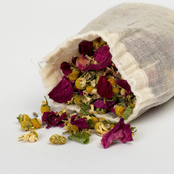 Bee Balm and Nettle closeup of muslin bag of peaceful mind bath tea on its side with contents of dried roses and more spilling out 