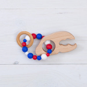 Baloo Baleerie lobster claw shaped wooden teether with ring of silicone beads in red, white, and blue with a wooden ring attached