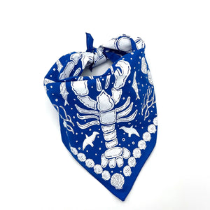 Royal blue nautical bandana by A Wee Maine Artist, tied in a stylish knot, featuring maritime-inspired design.