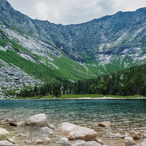 Scenic view of Katahdin Mountain during a hiking trip with Down East Adventures, featuring lush greenery and clear blue sky.