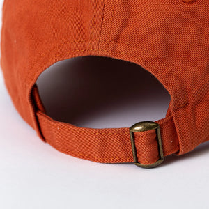 Rust-colored Katahdin cap by Bckwds Design Company featuring a classic, adjustable baseball cap style with a curved brim.