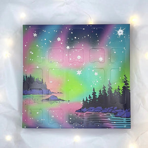 Advent calendar box with a scenic design of trees and water with a Northern lights design of colors and stars on a white background.