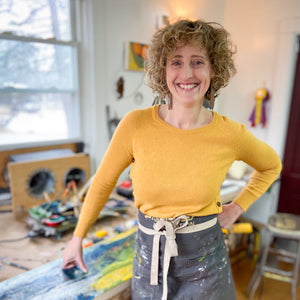 Helen standing with crossed legs during a Down East Adventures encaustic painting workshop session.