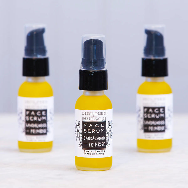 Glass vials of bright yellow sandalwood & primrose face serum with pump dispenser tops