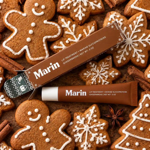 Marin Skincare Gingerbread Lip Treatment tube with festive gingerbread cookies in the background, showcasing nourishing lip care.