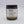 Wayward Chickadee Swiss Meadows scented candle in a glass jar with a lit wick and floral design, emitting a warm, inviting glow
