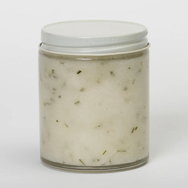 Bee Balm and Nettle back view of glass jar of evergreen forest bath & shower scrub showing the flecks of pine, fir, and cedar throughout the cream colored scrub