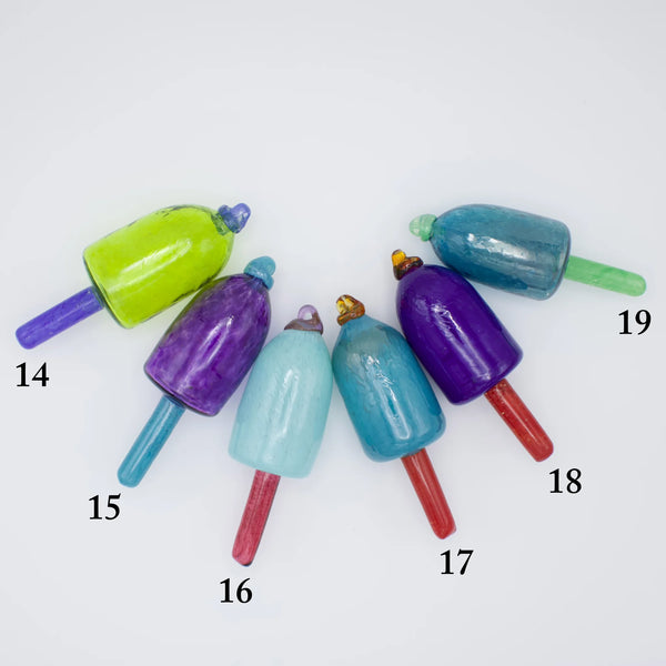 Group of colorful nautical glass buoy ornaments by Casco Bay Glassworks, showcasing vibrant glass floats in a seaside display.