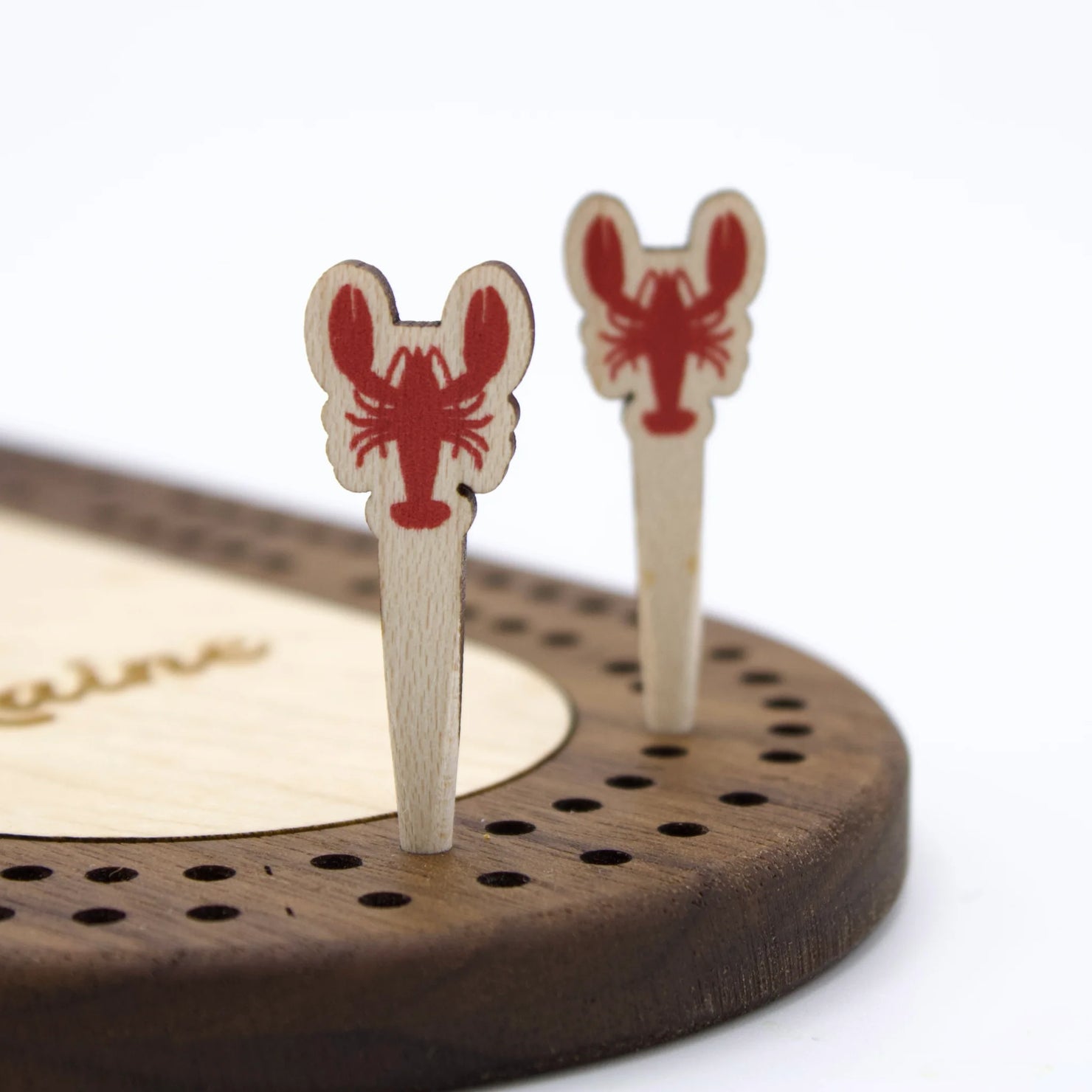 Colorful cribbage peg sets by Cast & Carve featuring lobster-shaped pegs on a wooden board.