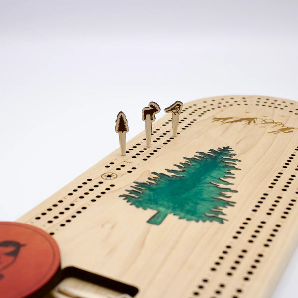 Cast & Carve Pine Tree Epoxy Cribbage Board with colorful pegs for traditional game play, featuring a pine tree design and epoxy finish.