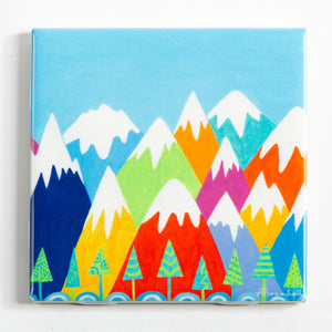 Festive Fish brand decorative trivets featuring colorful mountain and happy face designs on tile-style coasters.