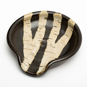 the round pottery spoon rest features two branching white birch trees with a black background