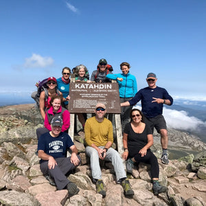 Hiker Emily standing on Katahdin Mountain during a Down East Adventures hiking trip, surrounded by scenic wilderness and blue sky