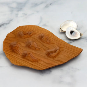 Small cherry wood hand-carved oyster platter by Oyster River Joinery, featuring a smooth, natural finish and intricate carving details.
