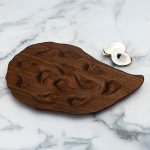 Hand-carved walnut oyster platter by Oyster River Joinery, showcasing a smooth, elegant serving board with natural wood grain.