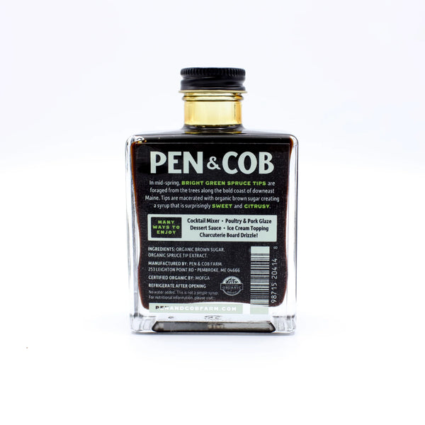 Back view of Pen and Cob Spruce Syrup bottle showing the label and dark amber syrup inside.