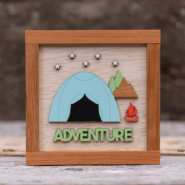 163 Design Company wooden frame and background with painted wooden tent with stars above, pine trees, mountain, campfire, and word ADVENTURE