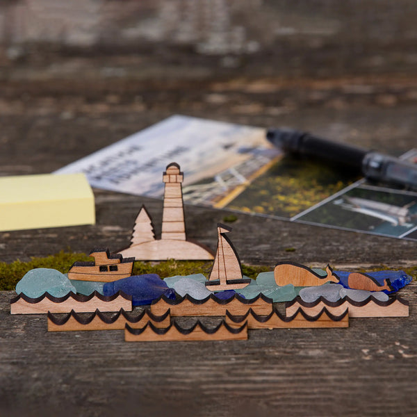 163 Design Company small pieces include lighthouse on island with pine tree, lobster boat, sail boat, whale, baby whale and waves