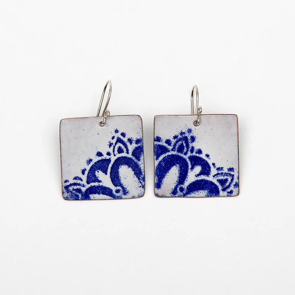 Blueberry Bay Jewelry white square copper enameled earrings hang from sterling silver ear wires and each one has a partial blue mandala design