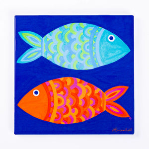 Two colorful festive fish trivets from Festive Fish with vibrant holiday-themed designs on ceramic surfaces.