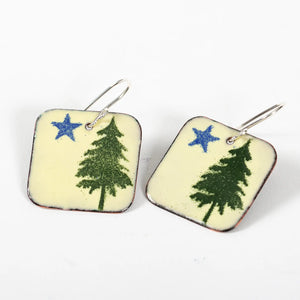Blueberry Bay Jewelry rounded square copper enameled earrings hang from a sterling silver ear wire and have a design of blue star and dark green pine tree on a cream background