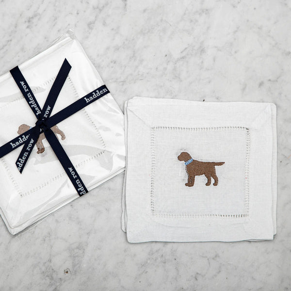 Linen cocktail napkin with an embroidered chocolate lab with a blue collar on a marble background