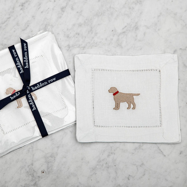 Linen cocktail napkin with an embroidered yellow lab with a red collar on a marble background