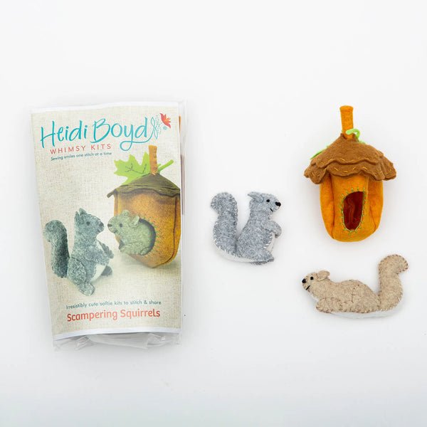Squirrels whimsy felting kit in clear plastic package next to completed examples of two squirrels and an acorn